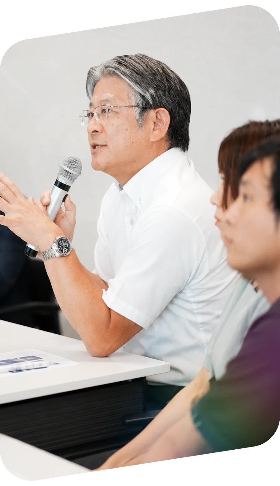会場でマイクを持って話す経営者